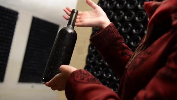 Ένα γυναικών κατέχει ένα μπουκάλι κρασί στην κάβα παλαίωσης. ΑΜΠΕΛΑΚΙ Μπορντό — Αρχείο Βίντεο