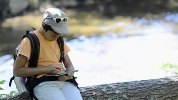 Ragazzino che cammina da solo in una foresta usando un tablet — Video Stock
