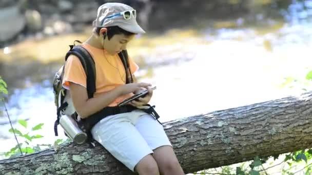 Ragazzino che cammina da solo in una foresta usando un tablet — Video Stock