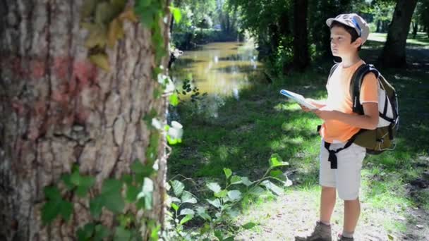 Küçük çocuk tek başına bir harita kullanarak bir ormanda yürüyüş — Stok video
