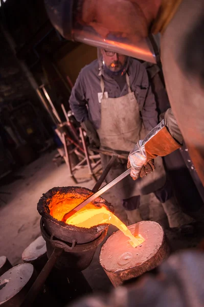 Fundición trabajador vertiendo metal caliente en el molde — Foto de Stock