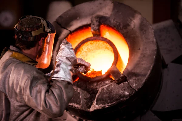 在防护服耙在工业炉中的钢铁工人 — 图库照片