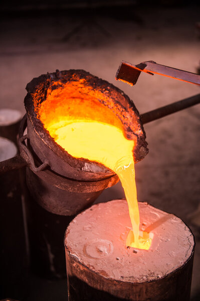 Foundry worker pouring hot metal into cast