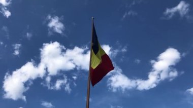 Romania flag waving with clouds and blue sky, medium shot of Romania flag