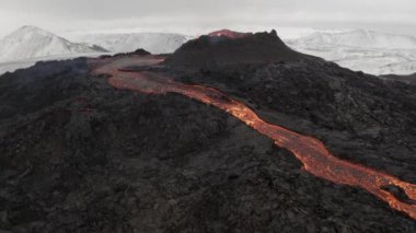 Flying Close to lava eruption volcano with snowy mountains4K drone shot from Iceland of Hot lava and magma coming out of the crater, April 2021 