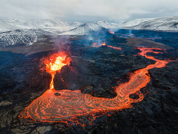 lava eruption volcano with snowy mountainsdrone view from Iceland of Hot lava and magma coming out of the crater, April 2021 