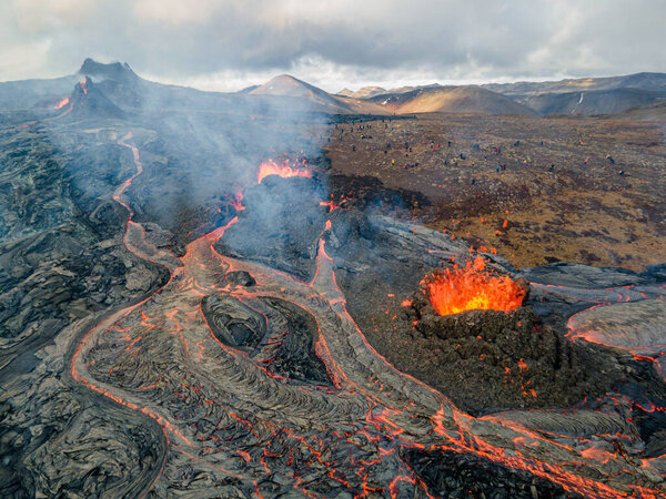lava eruption volcano with snowy mountainsdrone view from Iceland of Hot lava and magma coming out of the crater, April 2021 