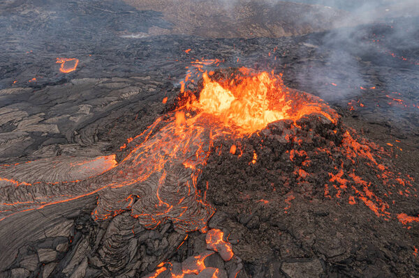 lava eruption volcano with snowy mountainsdrone view from Iceland of Hot lava and magma coming out of the crater, April 2021 