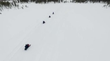 Kar motosikletleriyle Sefer Lapland Ormanı 'na Giren Hava Görüntülü İnsansız Hava Aracı, Laponya' daki donmuş kar araçları üzerinde bir sütunla turizm manzarası