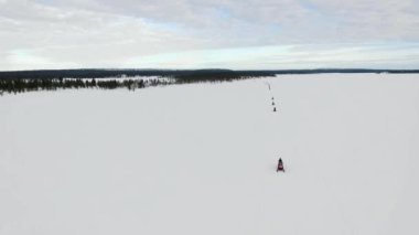 Laponya 'daki kar araçlarıyla yolculuk yapmak, Laponya' daki donmuş kar araçlarıyla ilgili bir sütunla turizmin insansız hava aracı görüntüsü