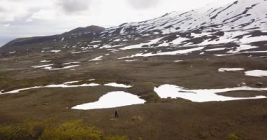 İzlanda 'nın açık arazisinde yürüyen yalnız bir yürüyüşçü, İzlanda' nın kayalık tarlaları ve dağları için hava aracı manzarası