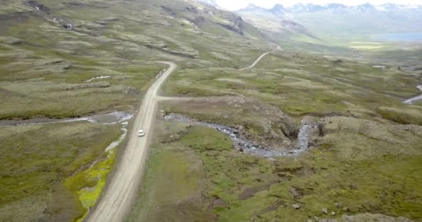 驾驶汽车在冰岛山区风景路 空中俯瞰白色私家车驾驶沿着土路在冰岛东部 2021年2月 — 图库视频影像