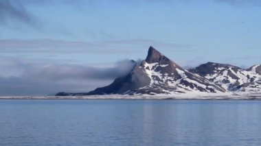 Deniz ve bulutlar ile karlı dağlar