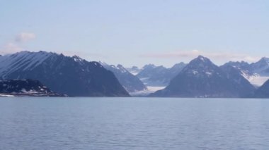 Deniz ve bulutlar ile karlı dağlar