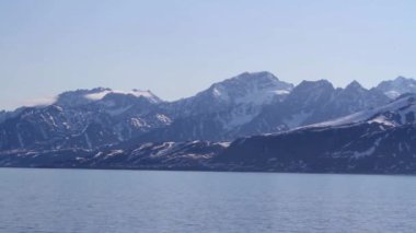 Deniz ve bulutlar ile karlı dağlar