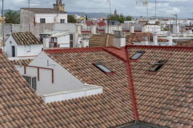 Cordoba 'nın beyaz ve kırmızı çatılarının manzaralı bir görüntüsü, arka planda şehrin silüeti var. Görüntü geleneksel Endülüs mimarisini, dar sokakları ve bu tarihi İspanyol şehrinin eşsiz atmosferini yakalıyor..