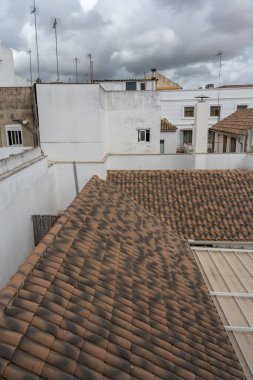 Cordoba 'nın beyaz ve kırmızı çatılarının manzaralı bir görüntüsü, arka planda şehrin silüeti var. Görüntü geleneksel Endülüs mimarisini, dar sokakları ve bu tarihi İspanyol şehrinin eşsiz atmosferini yakalıyor..