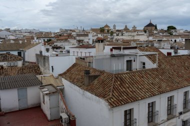 Cordoba 'nın beyaz ve kırmızı çatılarının manzaralı bir görüntüsü, arka planda şehrin silüeti var. Görüntü geleneksel Endülüs mimarisini, dar sokakları ve bu tarihi İspanyol şehrinin eşsiz atmosferini yakalıyor..