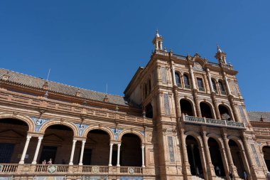 İspanya, Seville 'deki Plaza de Espaa' nın anıtsal mimarisinin ayrıntıları. Kemerleri, kolonları ve tipik Endülüs seramik süslemeleri olan yarı dairesel Rönesans Uyanışı binası. Şehrin en ikonik simgelerinden biri.