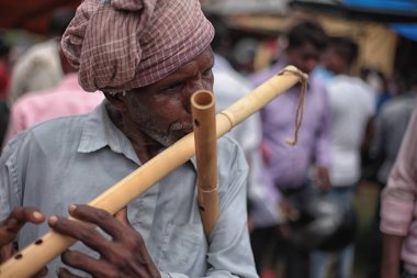 Jhargram, Batı Bengal, Hindistan 7 Temmuz 2019 yaşlı bir adam ahşap flüt çalıyor. Bir köy fuarında flütle müzik bestelemek..