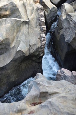 Dağlardaki kaya oluşumları arasında akan bir nehrin panoramik görüntüsü.