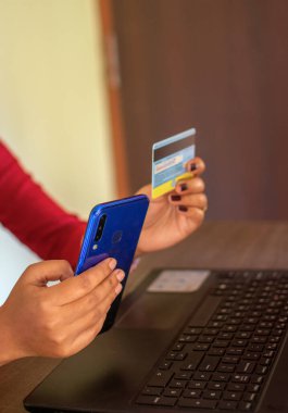 Cep telefonundan alışveriş yapmak ve satın almak için kredi kartı kullanan bir kadın. Seçici odak.