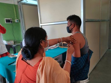 Jhargram, Batı Bengal, Hindistan-23 Şubat 2021: Bir tıp çalışanı, Jhargram Hastanesi COVID-19 aşı kampanyası sırasında Batı Bengal Genel Kurulu Seçim 2021 anket personeline ilk Covishield aşısını aşıladı.