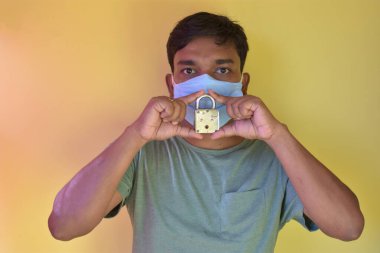 Sarı arka planda maske takan biri. Yeni Coronavirus 'un (COVID-19) etkisi nedeniyle işyeri veya mağaza kapanmış ve iflas etmiş durumdadır.).