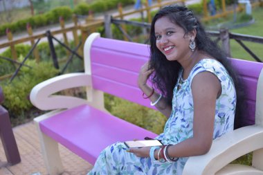 Cep telefonu kullanan ve dışarıda gülümseyen Hintli bir kadın..