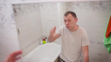 Yüzünü buruşturan genç adam, görünüşünden memnun değil.