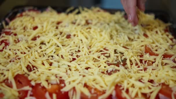 Homem polvilha pizza caseira com queijo ralado, close-up — Vídeo de Stock