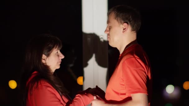 Férfiak és nők nézik és fogják egymás kezét, ahogy éjjel az ablaknál állnak. — Stock videók