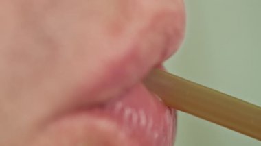 Plastik bir kokteyl tüpünden içki içen bir adam.