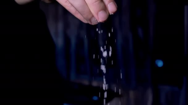 Αρσενικά δάχτυλα πάνω από μια κατσαρόλα με βραστό νερό, ρίχνει αλάτι στο τηγάνι, κοντινό πλάνο, αργή κίνηση, σκούρο φόντο — Αρχείο Βίντεο