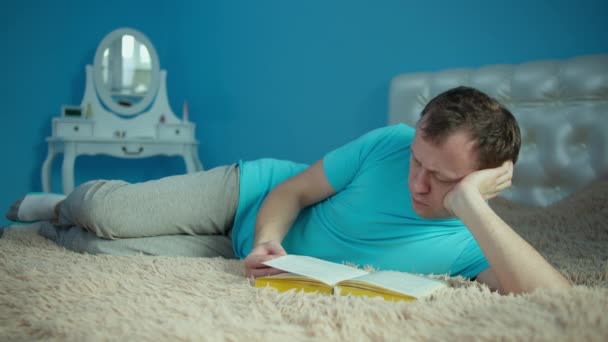 Portrait of a young man lying with a book in his hands — Stock Video