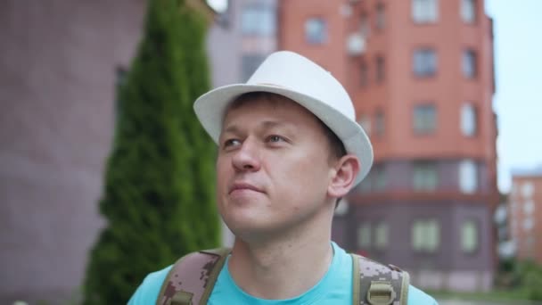 Young attractive man in hat walking in the city, camera tracking — Stock Video