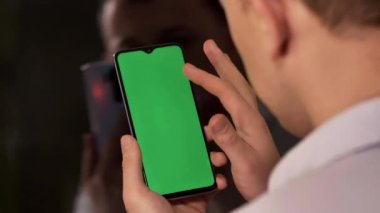 Telefonu olan genç adam parmağını ekranda gezdiriyor, kromakey, arka plan.