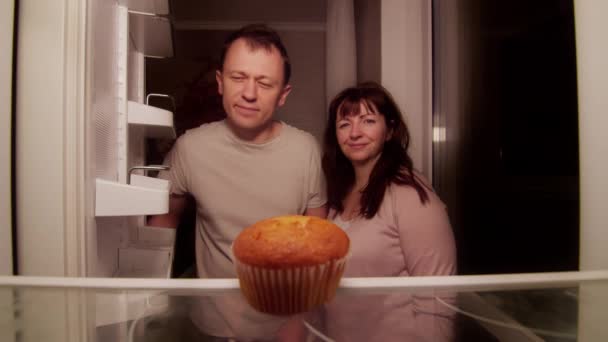 Una pareja de casados abre el refrigerador por la noche y encuentra allí un cupcake estropeado — Vídeo de stock