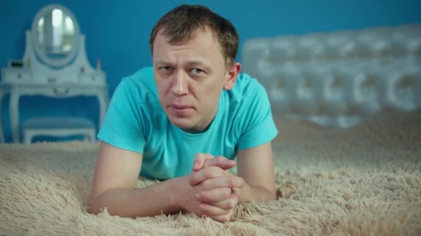 Misstrauensgefühle im Gesicht eines jungen Mannes, der auf dem Bett liegt — Stockvideo