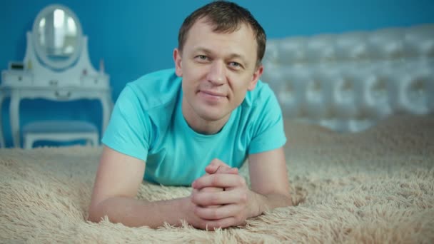 Zâmbind tânăr întins pe pat în dormitor și uitându-se la cameră — Videoclip de stoc