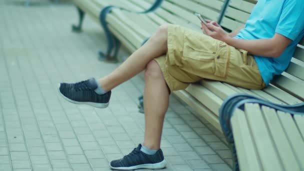 Hairy legs of a man in shorts sitting on a bench, tracking camera — Stock Video