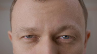 Genç bir adamın açık gri gözleri. Doğrudan kameraya bakıyorum, gri bir arka planda.