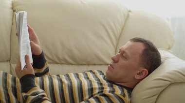 Genç bir adamın portresi. Kanepede uzanmış kitap okuyordum. Hareket eden kamera