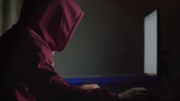 Unbekannter Mann mit Kapuze sitzt nachts am Computermonitor und knackt Passwort, Cyber-Angriff — Stockvideo