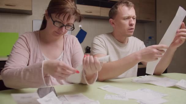 Een getrouwd stel in de avond zit aan de tafel kijkt door de cheques — Stockvideo