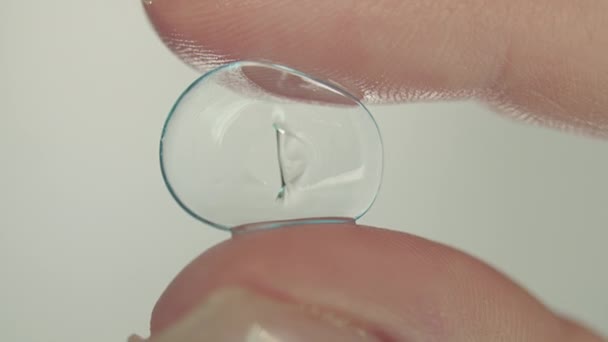 Dedos femeninos sosteniendo lente de contacto suave dañada, primer plano — Vídeos de Stock