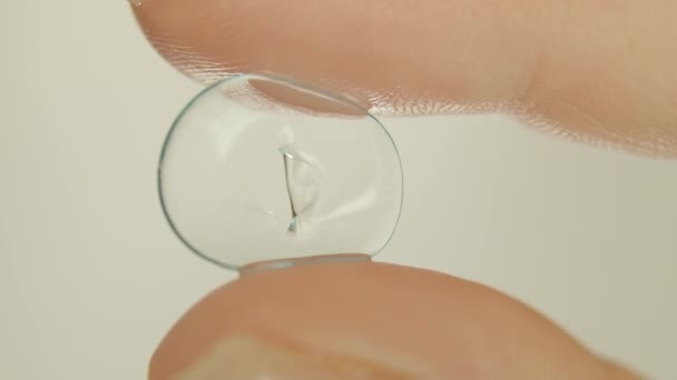 Nahaufnahme einer alten weichen Kontaktlinse in den Fingern, heller Hintergrund — Stockvideo