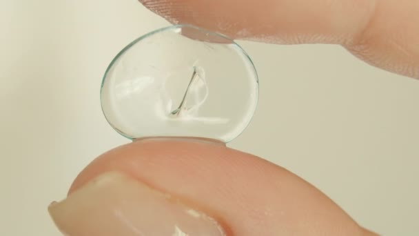 Close up of old soft contact lenses in womans fingers, light background — Stock Video
