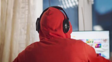 Evde, arka planda, kamera hareketinde çalışan kulaklıklı programcı