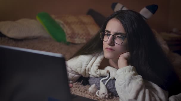 Diák éjszaka az ágyban, tanul egy laptopon, kamera követés — Stock videók